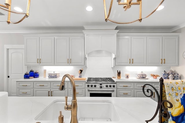 kitchen with backsplash, ornamental molding, light stone counters, and high end stainless steel range oven