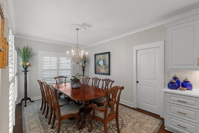 dining space featuring dark hardwood / wood-style flooring, a chandelier, and crown molding