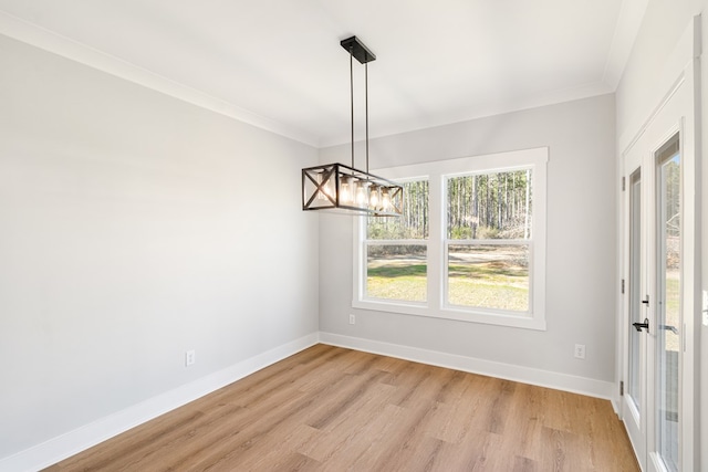 unfurnished dining area featuring baseboards, ornamental molding, a notable chandelier, and light wood-style floors