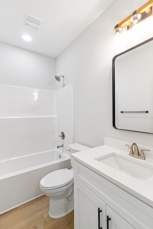 full bathroom with bathing tub / shower combination, visible vents, toilet, vanity, and wood finished floors