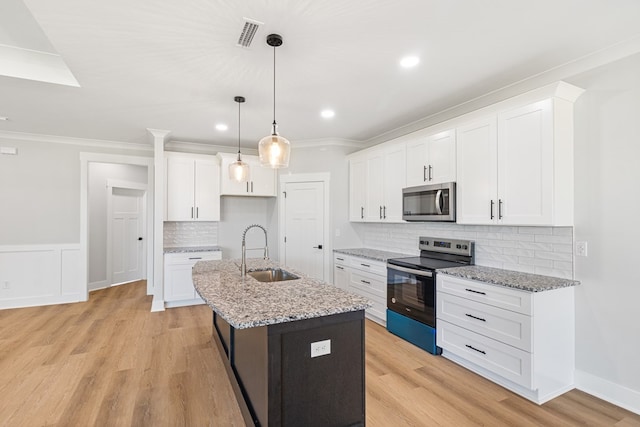 kitchen featuring electric range, stainless steel microwave, a center island with sink, and white cabinetry