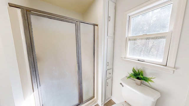 bathroom featuring a shower with shower door and toilet