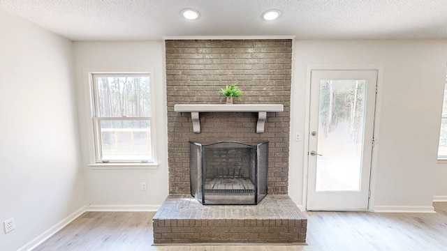 unfurnished living room featuring a textured ceiling, light hardwood / wood-style floors, and a healthy amount of sunlight