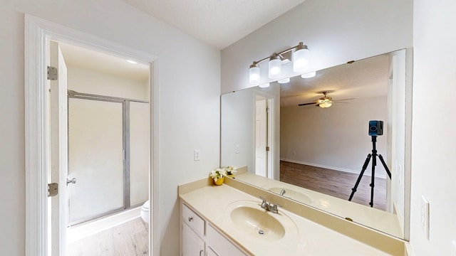 bathroom featuring hardwood / wood-style flooring, vanity, walk in shower, ceiling fan, and toilet