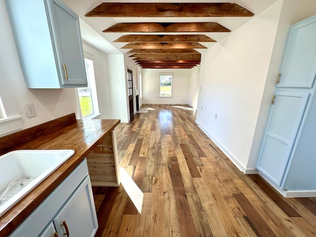 hallway with vaulted ceiling with beams, light hardwood / wood-style floors, and sink