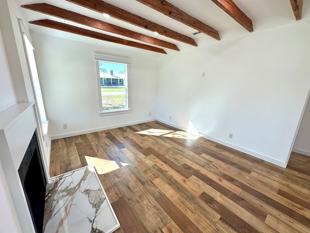 spare room featuring beamed ceiling and dark hardwood / wood-style flooring