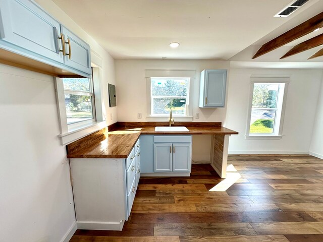 kitchen featuring butcher block countertops, plenty of natural light, white cabinets, and sink