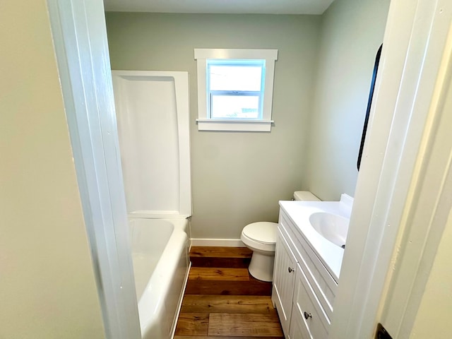 bathroom with hardwood / wood-style floors, vanity, a tub to relax in, and toilet