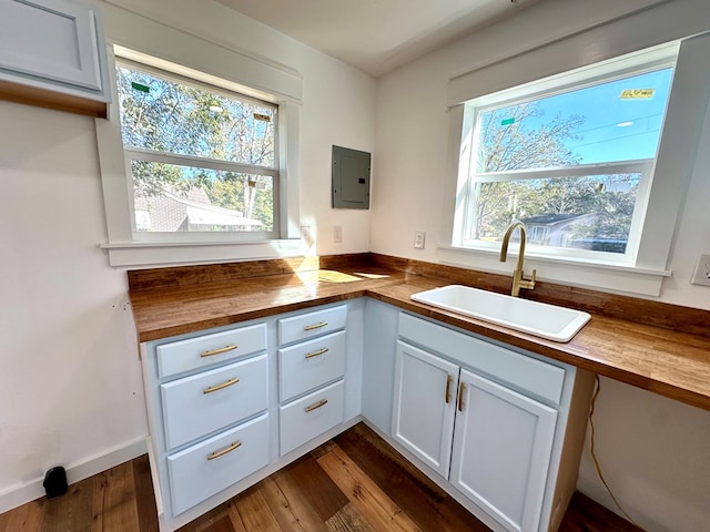 kitchen with butcher block countertops, sink, white cabinets, and dark wood-type flooring