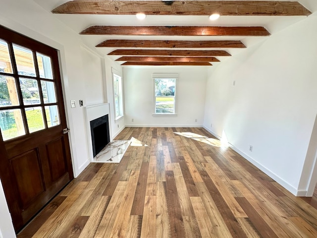 unfurnished living room featuring beam ceiling and light wood-type flooring