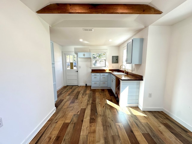 kitchen with electric panel, wooden counters, lofted ceiling with beams, sink, and dark hardwood / wood-style floors