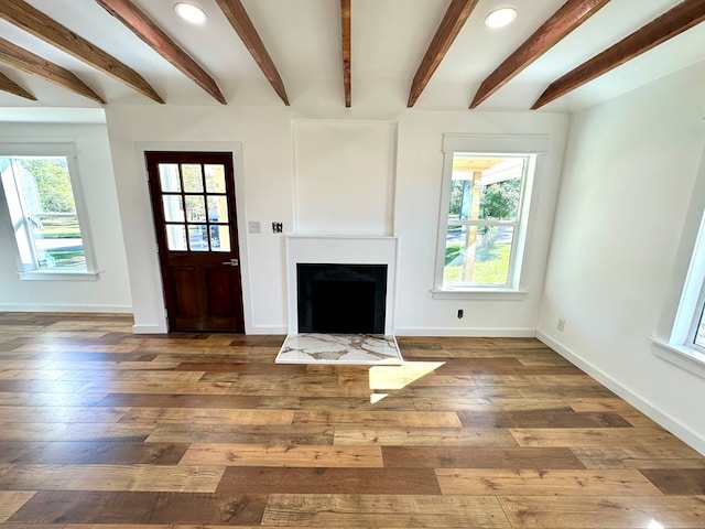 unfurnished living room featuring beam ceiling and dark hardwood / wood-style floors