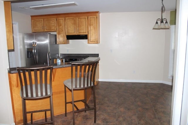 kitchen with stainless steel fridge with ice dispenser, a breakfast bar, and hanging light fixtures