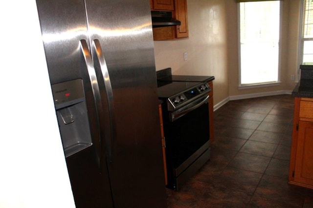 kitchen with appliances with stainless steel finishes, extractor fan, and dark tile patterned floors