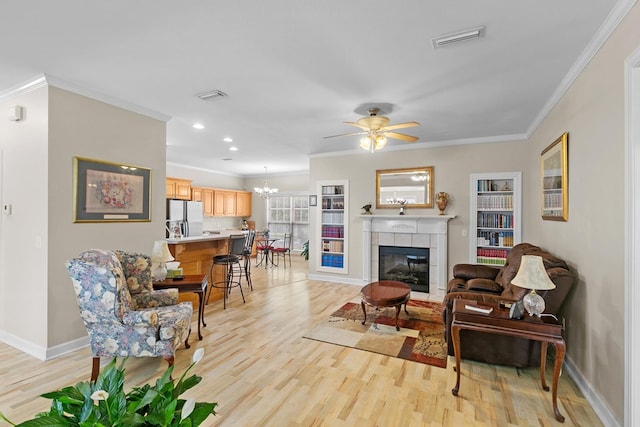 409 Drake Dr, Dothan, AL 36605 - living room featuring light wood-type flooring, ornamental molding, a tile fireplace, ceiling fan, and a chandelier