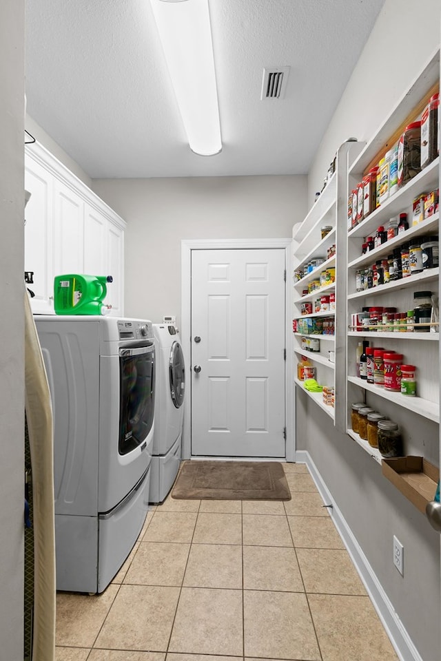 409 Drake Dr, Dothan, AL 36605 - laundry area featuring separate washer and dryer, cabinet space, light tile patterned flooring, and a textured ceiling