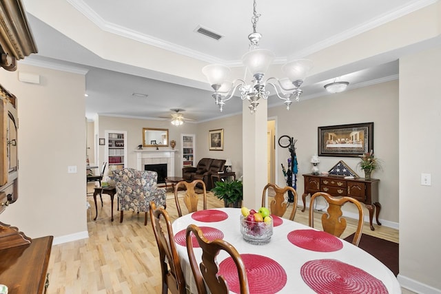 409 Drake Dr, Dothan, AL 36605 - dining space featuring a ceiling fan, a fireplace, light wood-style flooring, ornamental molding, and a chandelier