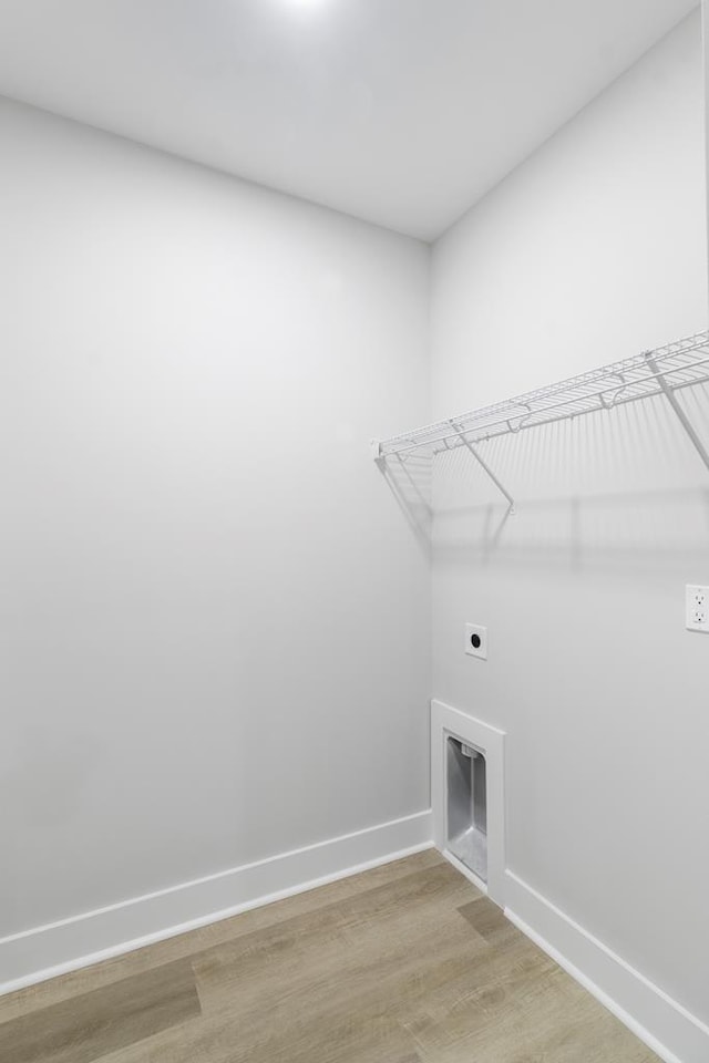 laundry area featuring laundry area, baseboards, electric dryer hookup, and light wood finished floors