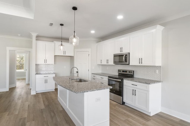 kitchen featuring a center island with sink, appliances with stainless steel finishes, light stone counters, white cabinetry, and a sink