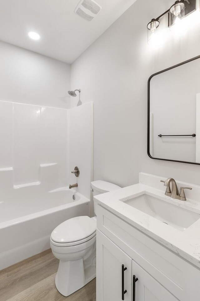 full bathroom featuring toilet, wood finished floors, vanity, visible vents, and shower / bathing tub combination