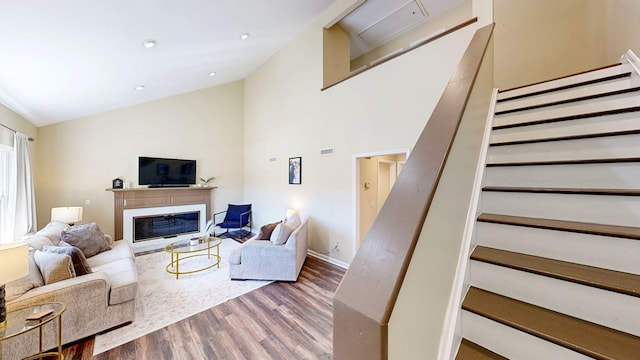 180 Fairway Woods Dr, Ozark, AL 36360 - living area featuring stairs, wood finished floors, a glass covered fireplace, high vaulted ceiling, and baseboards