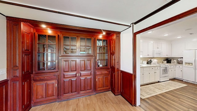180 Fairway Woods Dr, Ozark, AL 36360 - kitchen with white appliances, light wood-type flooring, white cabinetry, wainscoting, and glass insert cabinets