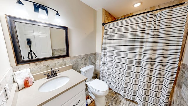 180 Fairway Woods Dr, Ozark, AL 36360 - full bathroom with tile walls, a wainscoted wall, toilet, vanity, and a shower with curtain