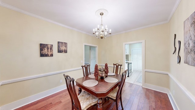 dining area featuring crown molding, a chandelier, and hardwood / wood-style flooring