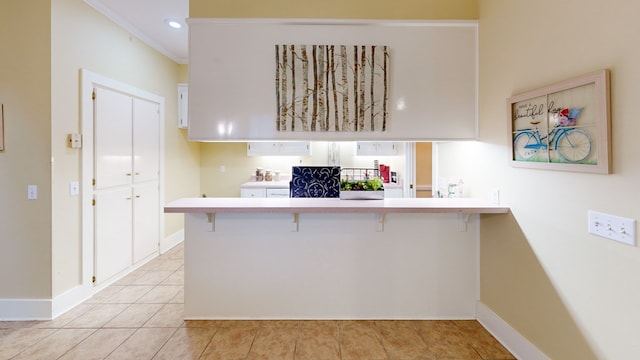 kitchen featuring white cabinets, crown molding, kitchen peninsula, and a breakfast bar area