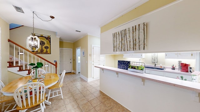 kitchen with white cabinetry, sink, hanging light fixtures, a notable chandelier, and ornamental molding