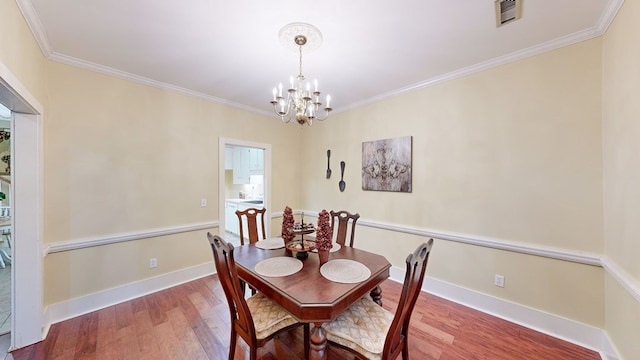 dining area featuring hardwood / wood-style floors, crown molding, and a notable chandelier