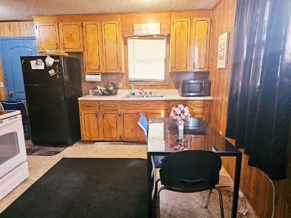 kitchen featuring sink, wooden walls, a textured ceiling, black fridge, and white electric range oven