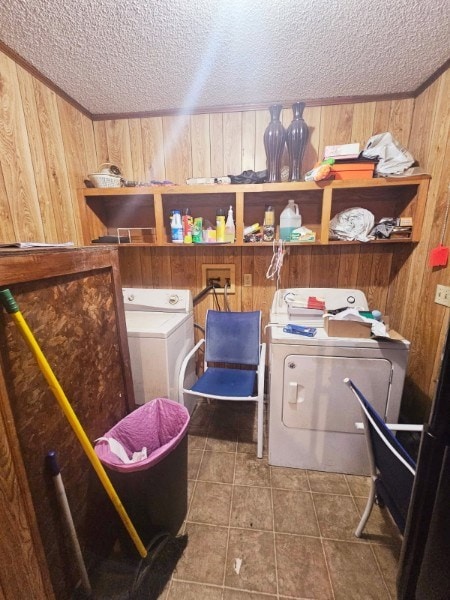 laundry area featuring washing machine and dryer, wooden walls, tile patterned flooring, and a textured ceiling