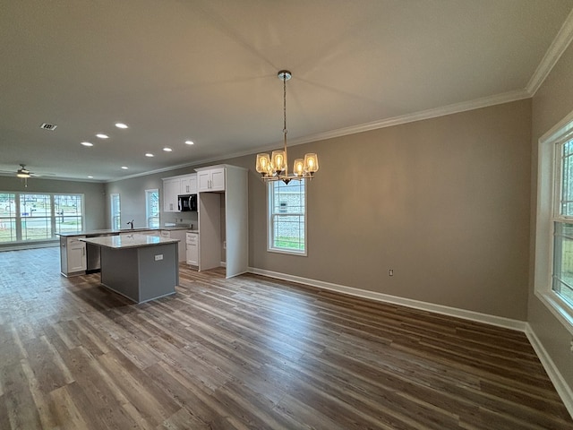 kitchen with hanging light fixtures, a kitchen island, dark hardwood / wood-style floors, a healthy amount of sunlight, and white cabinets