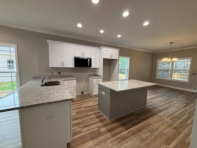 kitchen with sink, white cabinetry, light stone counters, dark hardwood / wood-style flooring, and pendant lighting