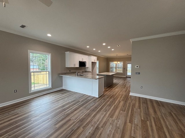 kitchen with sink, white cabinets, a chandelier, kitchen peninsula, and dark wood-type flooring