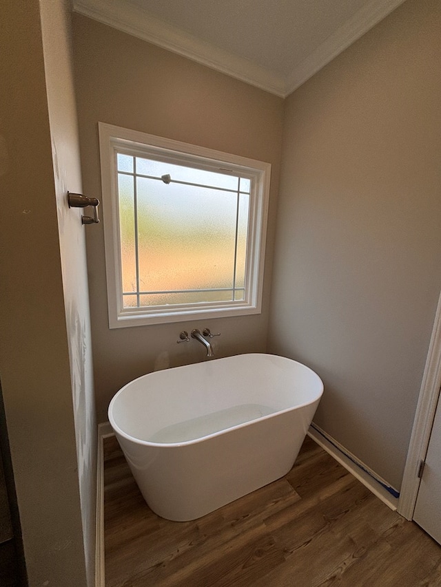 bathroom featuring a washtub, hardwood / wood-style flooring, and crown molding