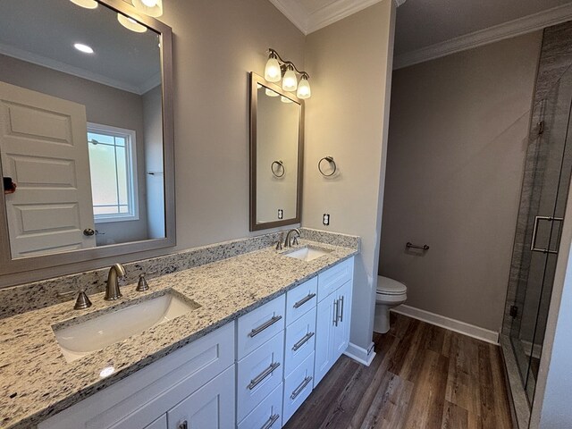 bathroom featuring a shower with door, hardwood / wood-style floors, vanity, ornamental molding, and toilet