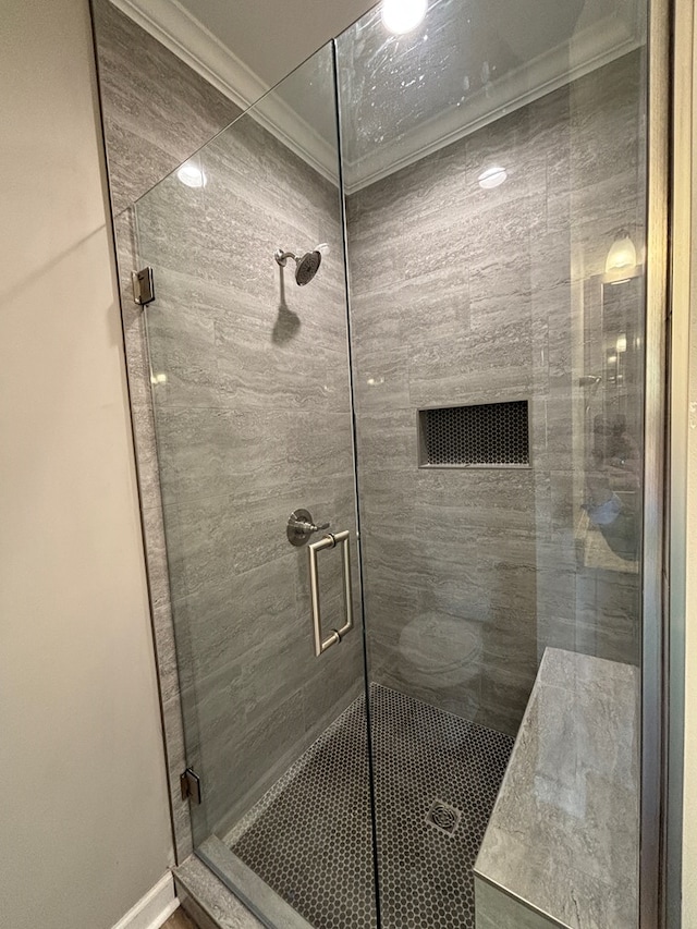 bathroom with a shower with door and ornamental molding