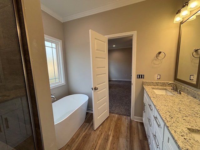 bathroom featuring ornamental molding, vanity, hardwood / wood-style floors, and a tub