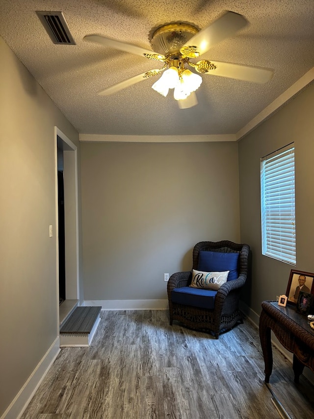 sitting room with visible vents, ceiling fan, a textured ceiling, wood finished floors, and baseboards