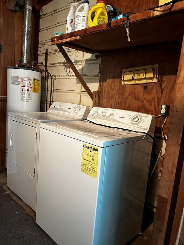 washroom featuring washing machine and dryer, laundry area, water heater, and wood walls