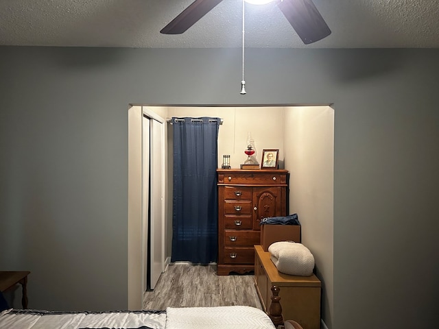 bedroom featuring light wood-style floors, ceiling fan, and a textured ceiling