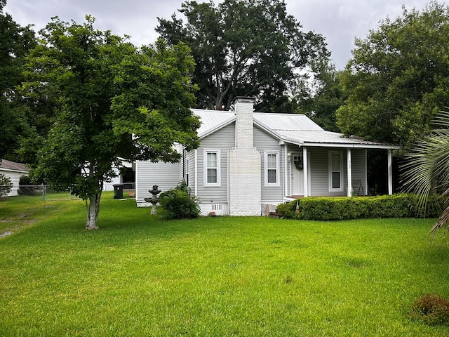 exterior space with metal roof, a lawn, a chimney, and crawl space