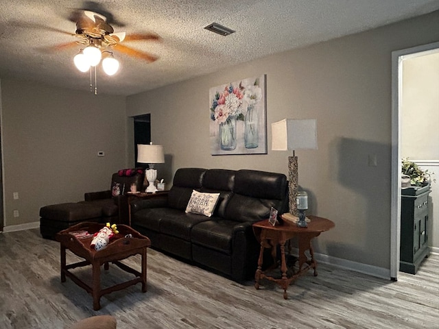 living area with light wood-type flooring, a ceiling fan, and a textured ceiling