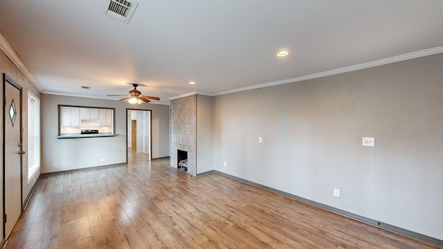 unfurnished living room with crown molding, ceiling fan, a tile fireplace, and light hardwood / wood-style flooring