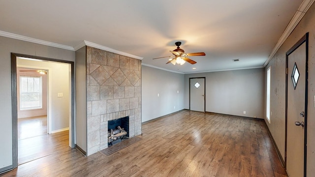 unfurnished living room with crown molding, a tiled fireplace, and hardwood / wood-style floors