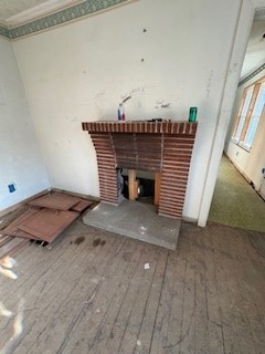 unfurnished living room with ornamental molding, a brick fireplace, and wood-type flooring