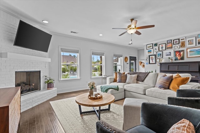 living area featuring ceiling fan, visible vents, dark wood-style floors, recessed lighting, and ornamental molding