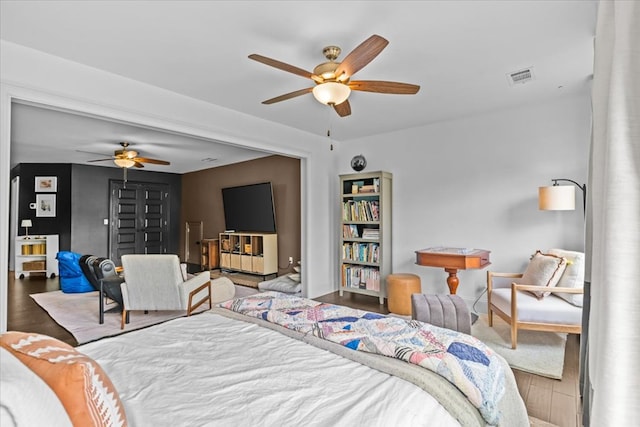 bedroom featuring baseboards, visible vents, wood finished floors, and a ceiling fan